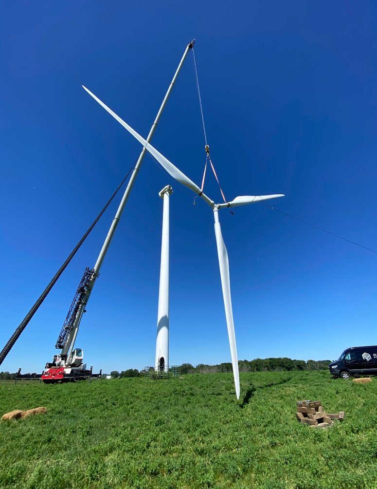 A crane lifting a turbine nacelle during a distributed wind installation in an open field